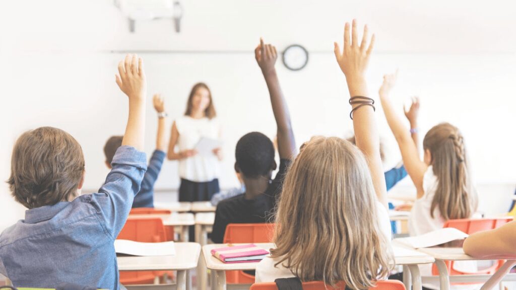 A classroom with students raised to participate in classroom discussion